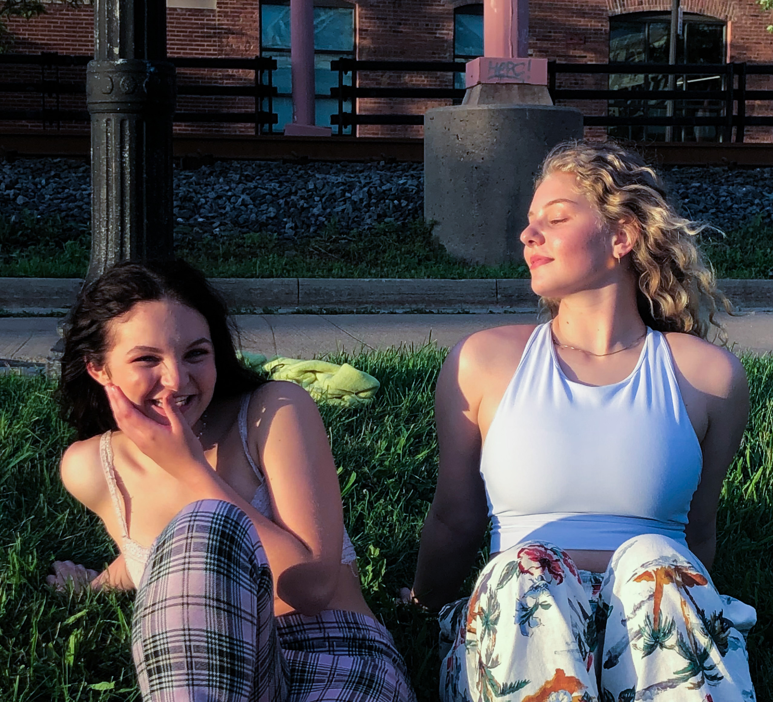 Owner of Stone Teller and her friend lauren sitting in front of the sun on grass.