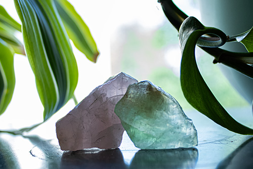 pink and green stone in front of a window with plants around it.