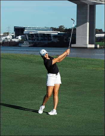 Girl swinging colf club on golf course.