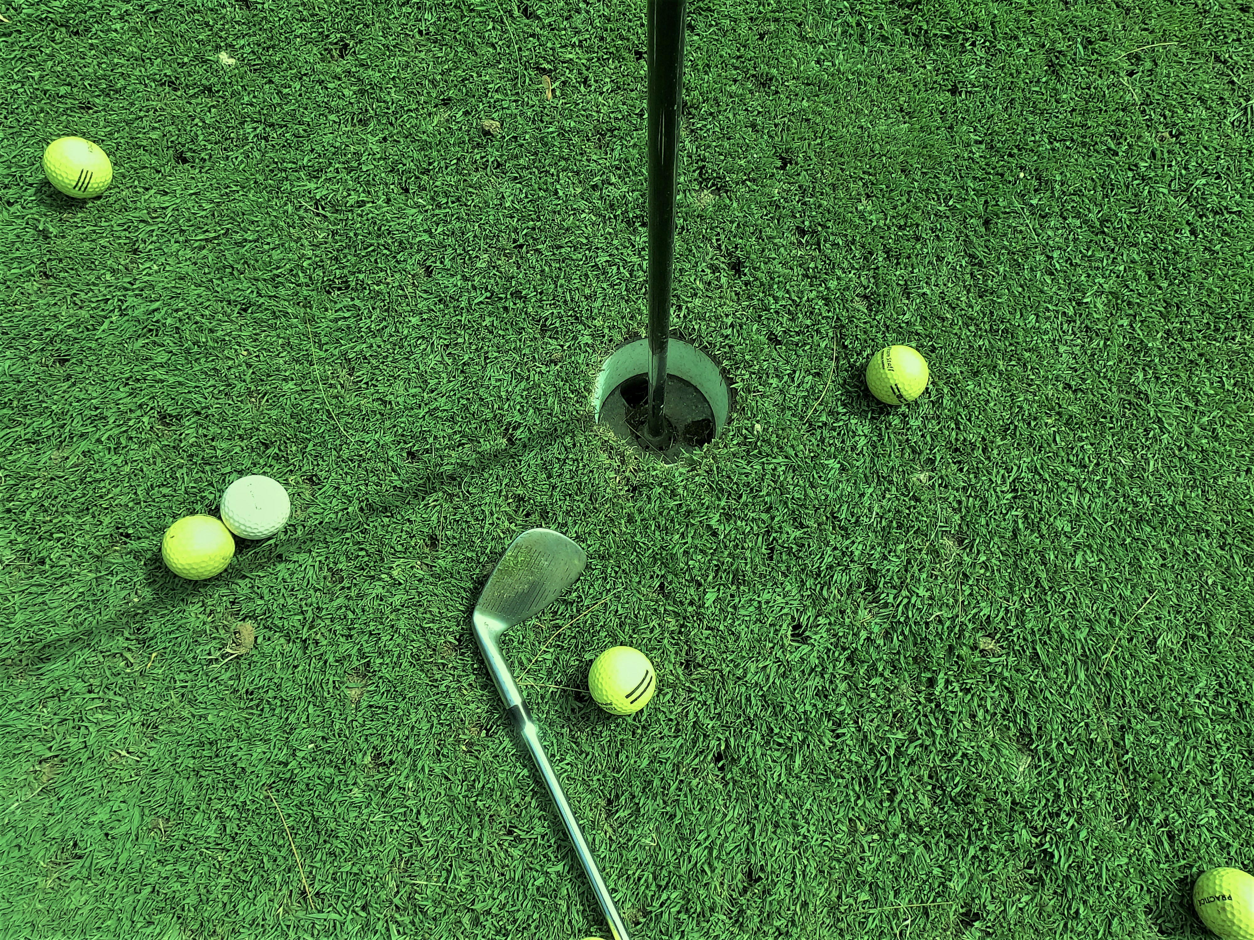 golf balls on a green near a golf hole.