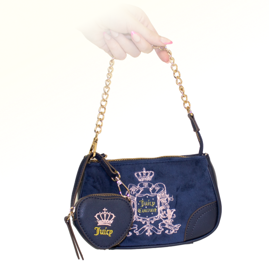 A small blue Juicy Couture purse that is velveteen and blue, embroidered with a pink Juicy Couture logo. A smaller heart coin purse with the word Juicy and a crown is attatched to the gold chain purse handle.