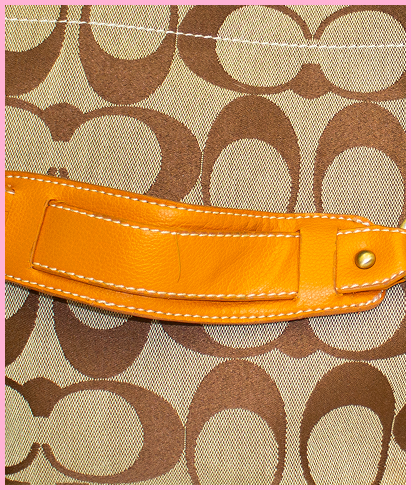 Detail shot of Cassie, brown Coach monogram pattern and orange/tan strap and white stitching up close.