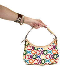 A hand holds a colorful handbag with a bold XO pattern (XOXO band), featuring hearts and circles.