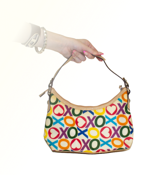 A hand holds a colorful handbag with a bold XO pattern (XOXO band), featuring hearts and circles.