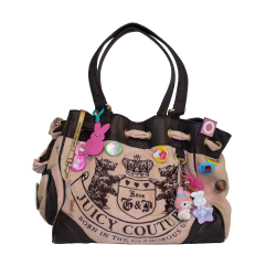 A Juicy Couture handbag with a bold crest logo, adorned with colorful pins and charms, including cartoon figures and embroidered dogs on the front.