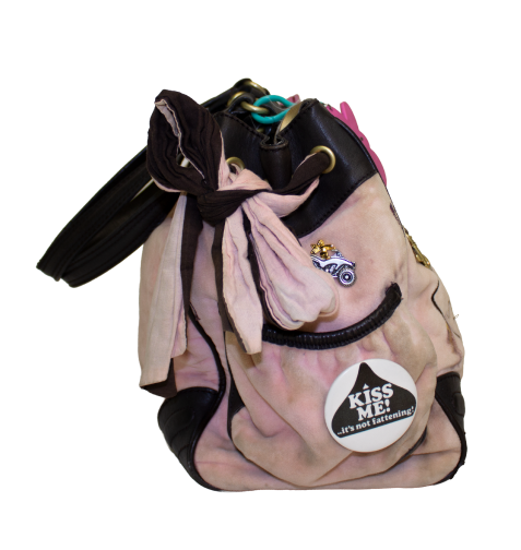 Side view of Juicy Couture handbag with a brown trim pocket and colorful pins.