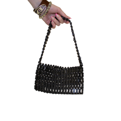 A hand holds a small black beaded purse with wooden peanut shaped beads.