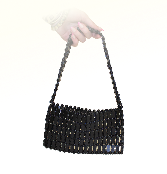 A hand holds a small black beaded purse with wooden peanut shaped beads.