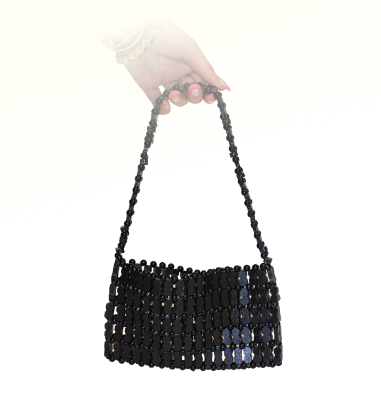 A hand holds a small black beaded purse with wooden peanut shaped beads.