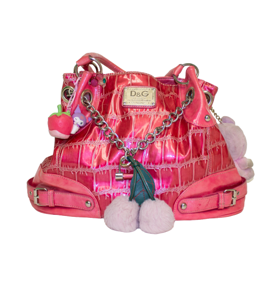 A shiny pink handbag with chain straps, pom-pom accents, and an alligator textured pattern, featuring a prominent D&G logo on the front.