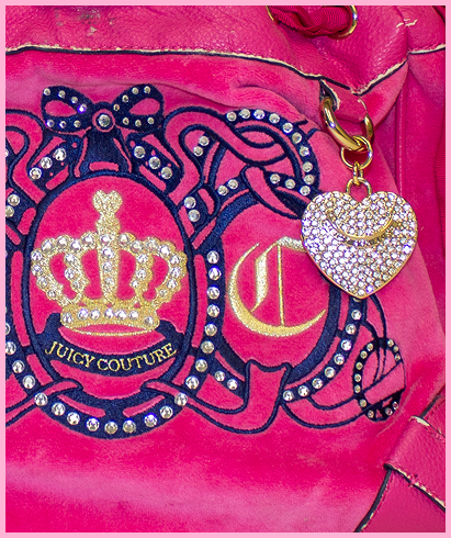 A detailed view of hot pink juicy couture purse with blue and gold embelleshments and the letters J and C.