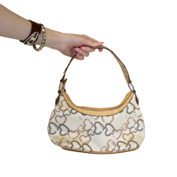 An XOXO brand tan purse, with a gray and brown heart pattern on it, silver hardware.
