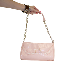 A hand holds a shiny pink clutch purse with a silver chain strap and laced bow detail on the front.