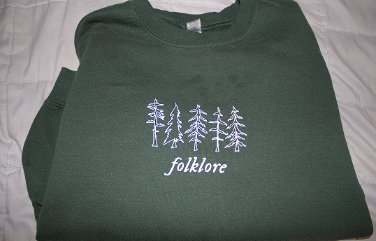Dark green sweatshirt that reads Folklore.