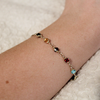 Model wearing bracelet with multicolored gems representing different Taylor Swift Albums.