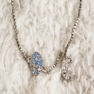 A silver bracelet that features a white crescent moon and a blue saturn planet.