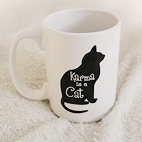 Overshot view of a white mug with a black cat that reads Karma is a Cat.