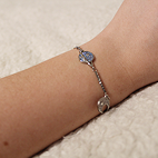 Model wearing a silver bracelet that features a white crescent moon and a blue saturn planet.