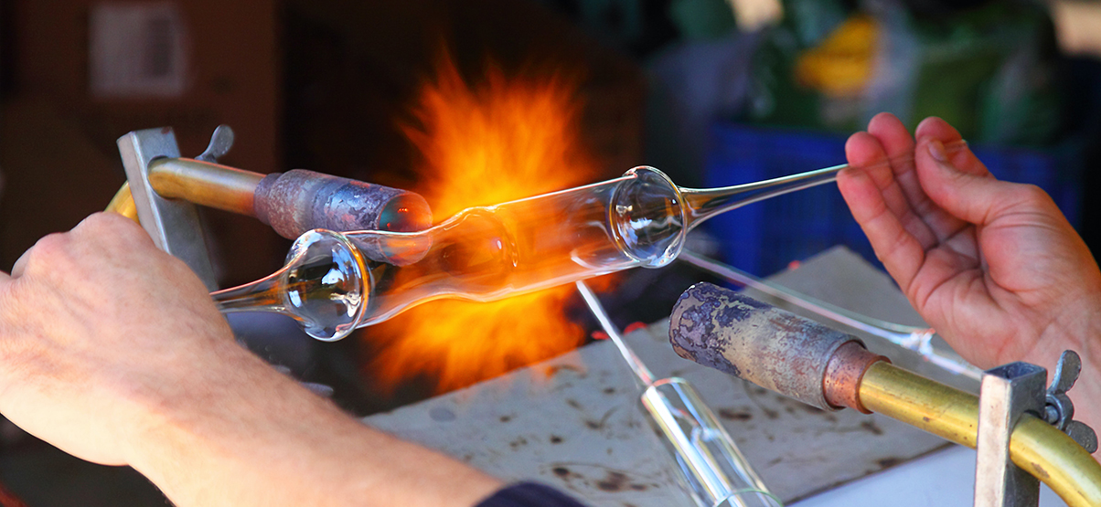 Artisan in Velaris blows glass at street fair 